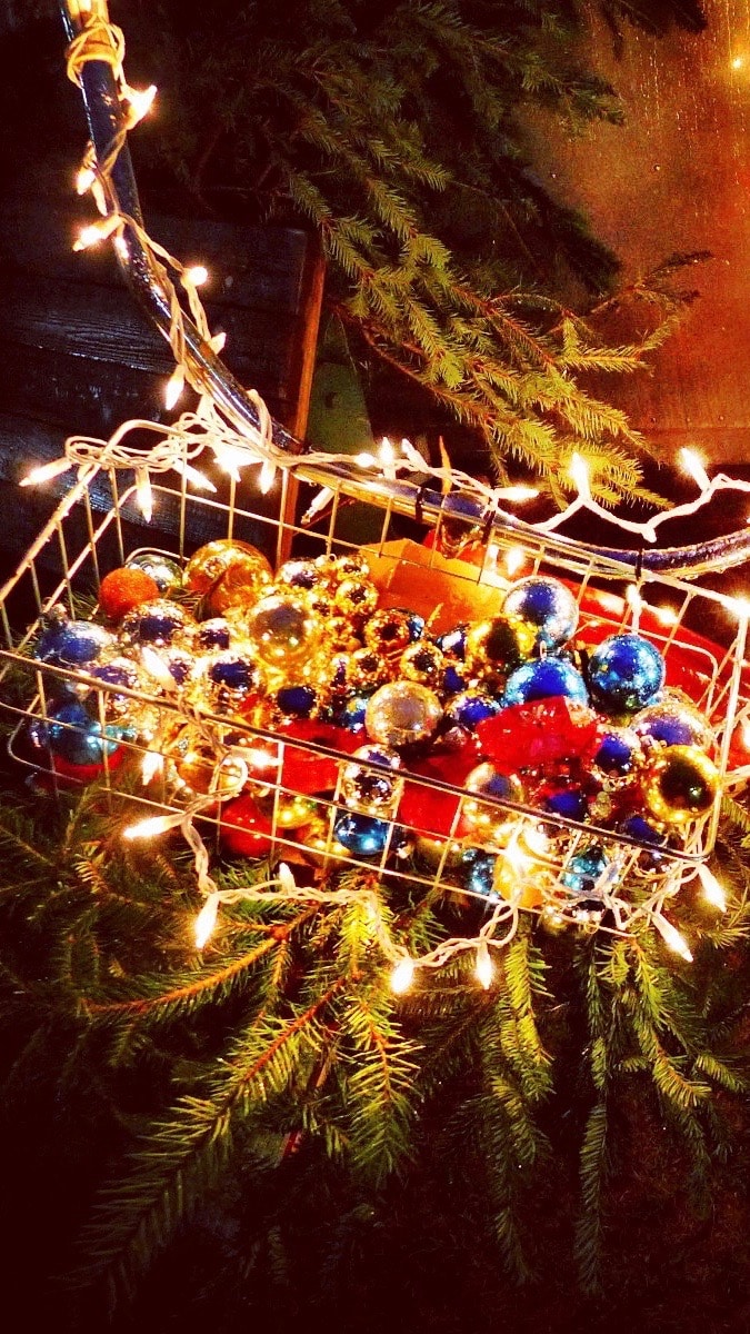 Sparkle and glow! Christmas wallpaper for iPhone 7. Glittering ornaments in a bicycle basket with lights and evergreens. Sparkly and festive!